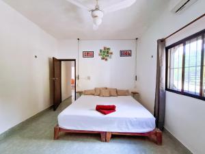 a bedroom with a white bed with a red pillow on it at Casa Jedidian in El Cuyo