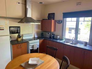a kitchen with a wooden table and a kitchen with a sink at The Cottage at Raheen in Mallacoota