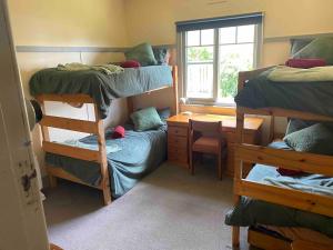 a bedroom with bunk beds and a desk and a window at The Cottage at Raheen in Mallacoota