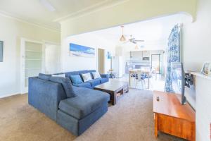 ein Wohnzimmer mit einem blauen Sofa und einem Tisch in der Unterkunft Cypress Cottage 26 Cypress Street Evans Head in Evans Head