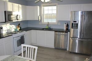ワーウィックにあるLake Shore Houseの白いキャビネットとステンレス製の冷蔵庫を備えたキッチン
