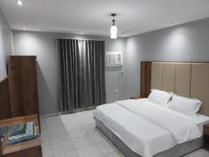 une chambre avec un grand lit blanc et une fenêtre dans l'établissement تميز الحمدانية Tamayoz Al-Hamdaneyah, à Djeddah
