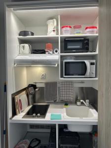 an open kitchen with a microwave and a sink at Ti Bel Soley climatisé vue mer avec réservoir d'eau in Saint-François