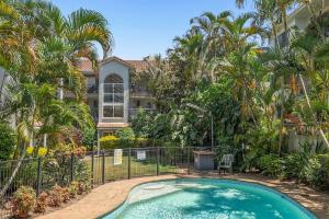 a swimming pool in front of a house with palm trees at Villa Sienna Hideaway 2 min walk to tramline in Gold Coast