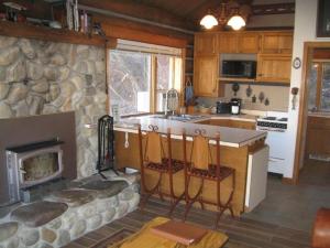 a kitchen with a stone fireplace and a stove at Rocky Mountains Nature Escape: Amazing Log Cabin with a Hot Tub in Darby, MT in Peaks and Pines Park