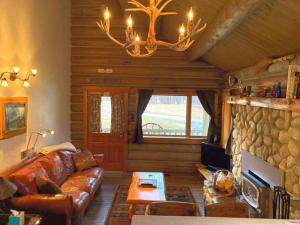 a living room with a leather couch and a fireplace at Rocky Mountains Nature Escape: Amazing Log Cabin with a Hot Tub in Darby, MT in Peaks and Pines Park +10 photos