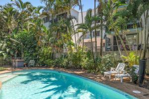a swimming pool in front of a building with palm trees at Villa Sienna Hideaway 2 min walk to tramline in Gold Coast