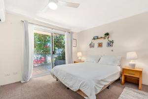 a white bedroom with a bed and a sliding glass door at Villa Sienna Hideaway 2 min walk to tramline in Gold Coast +12 photos