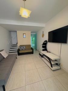 a living room with a couch and a flat screen tv at Casa em condominio bem no centro in São Sebastião