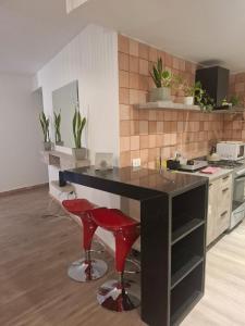 une cuisine avec un comptoir noir et deux tabourets rouges dans l'établissement Casa Magna, à San Miguel de Tucumán