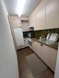 a kitchen with white cabinets and a white refrigerator at Hostel I Love Sg in St. Gallen