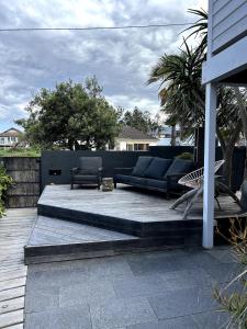 eine Terrasse mit einem Sofa und Stühlen auf einer Terrasse in der Unterkunft The Coastal Cool Room in Narrabeen + 7 Fotos