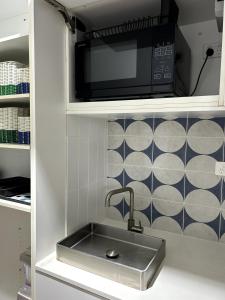 eine Küche mit Spüle und Mikrowelle in der Unterkunft The Coastal Cool Room in Narrabeen