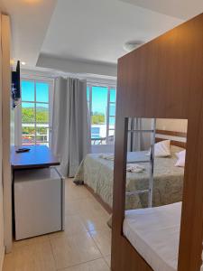 a bedroom with two beds and a desk and a balcony at Residencial Portoveleiro in Cabo Frio
