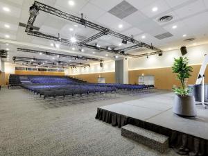 een grote zaal met blauwe stoelen en een podium bij Novotel Paris Est in Bagnolet