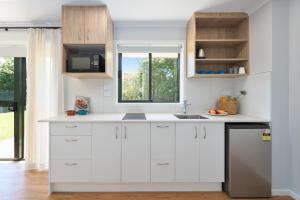 オークランドにあるAlbany Oak Motelの白いキャビネットと窓のあるキッチン