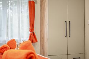 a bedroom with a bed with an orange curtain and a cabinet at Astoria Lodge Smart Modern 2-Bedroom Holiday Lodge Milford on Sea in Milford on Sea
