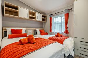two beds in a room with orange pillows at Astoria Lodge Smart Modern 2-Bedroom Holiday Lodge Milford on Sea in Milford on Sea