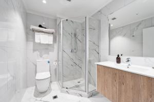 a bathroom with a shower and a toilet and a sink at Albany Oak Motel in Auckland
