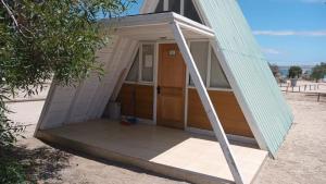 a small building with a door on the beach at Camping Corfo in Bahia Inglesa