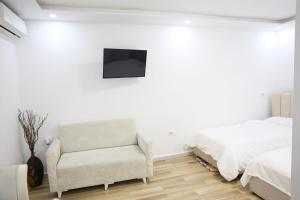 a bedroom with a bed and a chair and a television at The Central Spot in Tirana