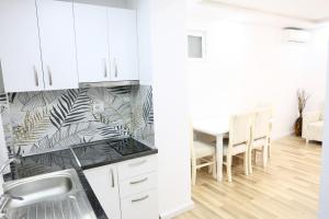 a kitchen with white cabinets and a dining room with a table at The Central Spot in Tirana