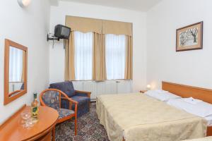 um quarto de hotel com duas camas e uma cadeira em City Club Prague em Praga