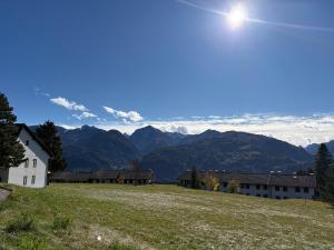 una casa en una colina con montañas al fondo en Mansarda Veronza, en Castello di Fiemme