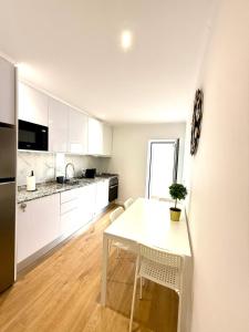 eine Küche mit weißen Schränken und einem weißen Tisch in der Unterkunft Casa da Vila Messines in São Bartolomeu de Messines