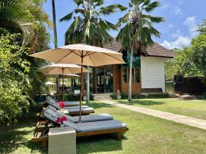 un grupo de tumbonas con sombrillas frente a un edificio en Umbelina Pousada Boutique, en Porto de Galinhas