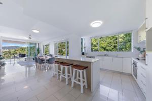 エアリービーチにあるVilla 59 - Pool, Ocean Views, Wifiの白いキャビネットとテーブルと椅子のあるキッチン