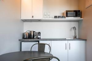Una pequeña cocina con una mesa y un microondas. en Tekapo Haven with Deck and Stargazing Sky, en Lake Tekapo