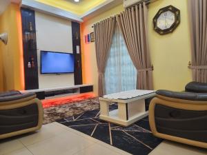 a living room with a tv and a table and a clock at HOMESTAY RIZQI - MUS LIM Only in Air Molek