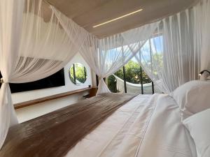 Un dormitorio con una cama blanca con una ventana. en Umbelina Pousada Boutique, en Porto de Galinhas