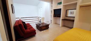 a living room with a red chair and a tv at MINI PINI BIRD WATCHING AND CENOTE Loft in Cozumel +32 photos