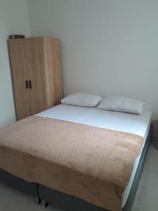 a bed with two pillows and a wooden cabinet at Beautiful apartment 5 minutes from the Historic Center in Cartagena de Indias +15 photos