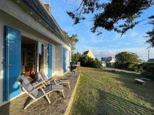 a patio with two lounge chairs on the side of a house at Holiday Home in Plozévet near Beaches in Plozévet