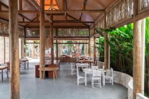 ein Restaurant mit Tischen, Stühlen und Pflanzen in der Unterkunft Pousada Do Rio Barreirinhas in Barreirinhas