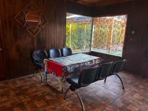 Un comedor con mesa y sillas y una ventana. en Cabaña Azul, en Vallenar