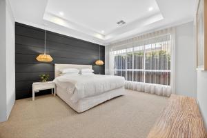 a bedroom with a white bed and a window at Coastal Luxe 4-Bed House in Madora Bay in Singleton