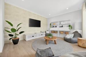 a living room with a tv on a wall at Coastal Luxe 4-Bed House in Madora Bay in Singleton