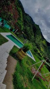 a house on a hill with a pool and a chair at Cabaña rústica con encanto y luces cálidas para noches inolvidables in Apuela