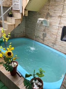 un bassin de détente avec une cascade et des plantes en pot dans l'établissement Pousada e Restaurante Toca do Camarão Gourmet, à Maricá