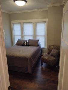 a bedroom with a bed and a chair and windows at City Getaway in Midland