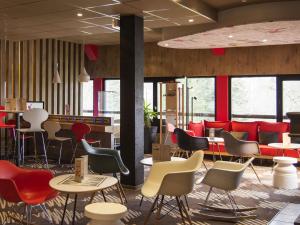 a restaurant with colorful chairs and tables and a bar at ibis Egletons in Égletons