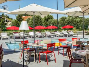 a restaurant with tables and chairs and umbrellas at ibis Orange Centre in Orange