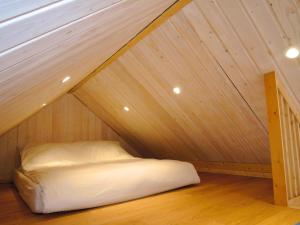 een bed op een zolder met een houten plafond bij Holiday homes with swimming pool, close to the sea in Wapnica +19 foto's