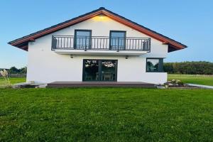 a white house with a balcony and a lawn at Green Hill Domyslow, 6 persons in Domysłów