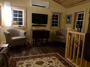 a living room with a flat screen tv and chairs at Rush River Cottage & Gardens in Ellsworth