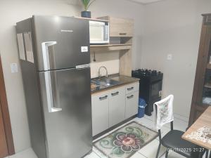 een keuken met een roestvrijstalen koelkast en een magnetron bij Apartamento Ótima Localização Turismo Faculdade in Bento Gonçalves